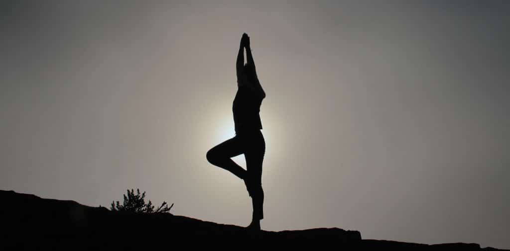 Woman standing on one leg balanced with the light behind her. mindfulness.